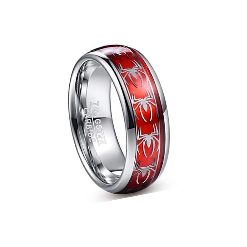 K&ouml;nnte beinhalten: Ein silberner Ring aus Wolframcarbid mit einer roten Einlage, die ein sich wiederholendes Spinnenmotiv zeigt. Der Ring ist mit "TUNGSTEN CARBIDE" graviert.