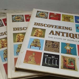 May include: Three vintage hardcover books titled "Discovering Antiques: The Story of World Antiques". The cover features a colorful collage of antique objects, including a clock, a chair, a rocking horse, and a goblet.