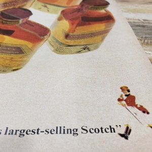 May include: A vintage advertisement for a brand of Scotch whisky. The ad features a close-up of several bottles of Scotch whisky and the text "world's largest-selling Scotch".