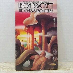 May include: A paperback science fiction novel cover with a colorful illustration of a futuristic city with a man and two creatures. The title of the book is "The Nemesis From Terra" by Leigh Brackett.