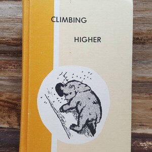 May include: A yellow and cream colored book with the title "Climbing Higher" and a black and white illustration of a bear climbing a tree.