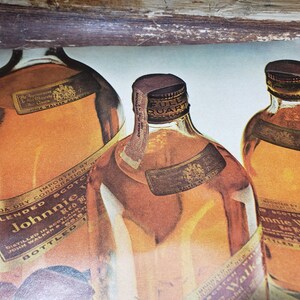 May include: Three glass bottles of blended Scotch whisky. The bottles are labeled "Johnnie Walker Red Label" and "Johnnie Walker Black Label". The bottles are on a light blue background.