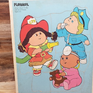 May include: A Playskool jigsaw puzzle featuring four Cabbage Patch Kids dolls dressed as a firefighter, a police officer, a doctor, and a nurse. The puzzle is made of wood and has 24 pieces. The puzzle is for ages 2-5.