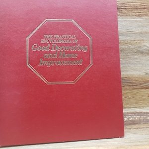 May include: A red hardcover book with a gold octagon on the front. The octagon has the text "The Practical Encyclopedia of Good Decorating and Home Improvement" in gold lettering.