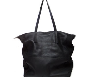 May include: A black leather tote bag with a single top handle. The bag has a large main compartment and a zippered closure.