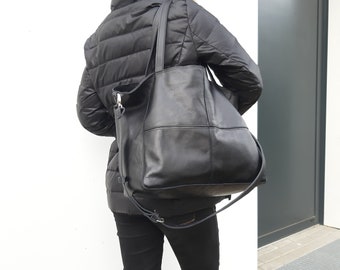 May include: A black leather tote bag with a long strap. The bag has a zipper closure and a flap with a buckle.
