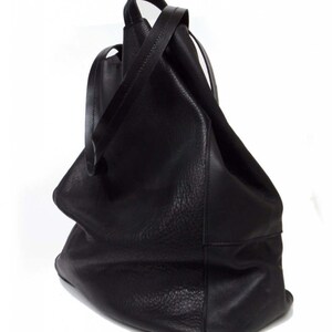 May include: A large, black leather tote bag with a slouchy, unstructured design. The bag has two long straps and a wide opening.