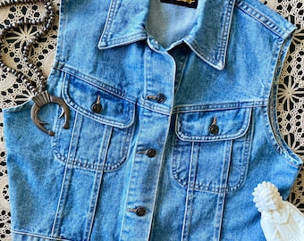 May include: A blue denim vest with a button closure and two front pockets. The vest has a label that reads "Twentieth Century".