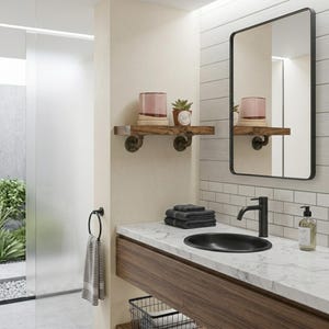 May include: A bathroom vanity featuring a white marble countertop, a black oval sink, and a black faucet. Above, a rectangular mirror with a black frame hangs next to a wooden wall shelf supported by dark metal pipe brackets holding a plant and candle.