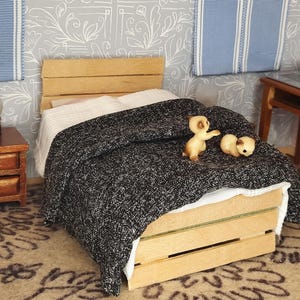 May include: A miniature wooden bed with a black and white patterned blanket and two small beige animal figurines. The bed has a wooden headboard and footboard and a slatted base.