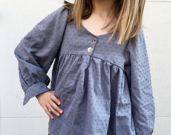 May include: A grey, long-sleeved, button-up blouse with a textured, dotted pattern. The blouse has a slightly gathered neckline and long, slightly puffed sleeves.