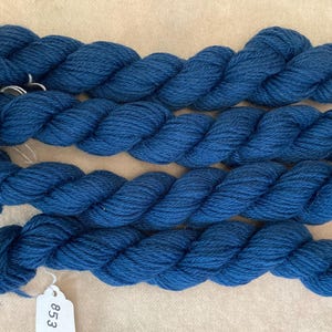 May include: Four skeins of deep blue yarn, twisted together. The yarn is labeled with the number "853".