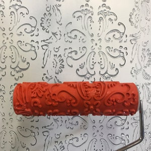 May include: A red paint roller with a paisley pattern. The roller is on a white background with a similar paisley pattern.