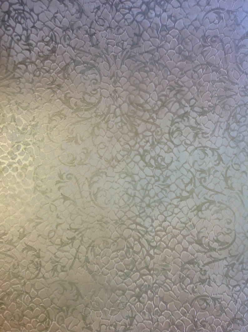 May include: A textured, light beige background with a subtle, repeating pattern of swirling vines. The pattern is embossed and creates a raised, three-dimensional effect.