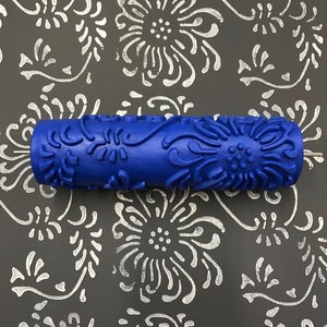 May include: A blue paint roller with a floral design. The roller is used to create a decorative pattern on walls or other surfaces.