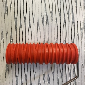 May include: A red textured paint roller with a metal handle. The roller has a repeating pattern of curved lines.