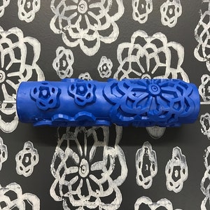May include: Blue paint roller with a floral design. The roller is used to create a decorative pattern on walls or other surfaces.