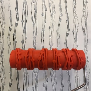 May include: A red rubber roller with a repeating pattern of vines and berries. The roller is attached to a metal handle.