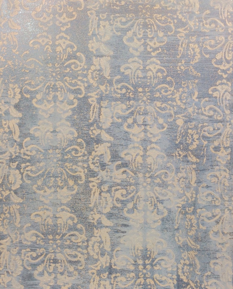 May include: A close-up of a textured surface with a light blue background and a beige pattern of repeating floral designs.