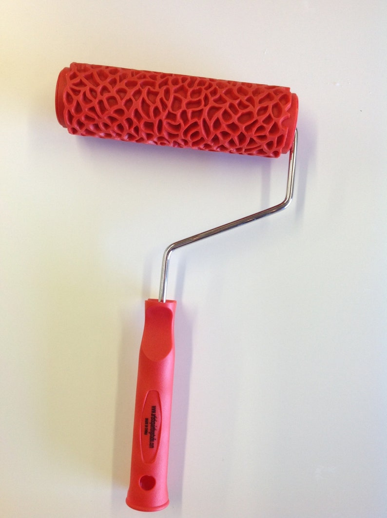 May include: Red paint roller with a textured pattern and a silver handle. The handle has a red plastic grip with the text "wooddesigns.com" printed on it.