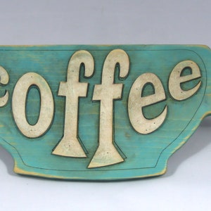 May include: A teal blue wooden coffee cup sign with the word "coffee" cut out in white.