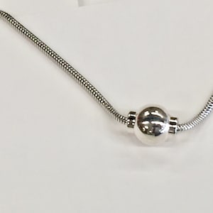 May include: A silver chain necklace with a single round silver bead pendant.