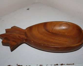 May include: A wooden pineapple-shaped bowl with a natural brown finish. The bowl is carved to resemble a pineapple with a detailed top and a smooth, rounded interior.