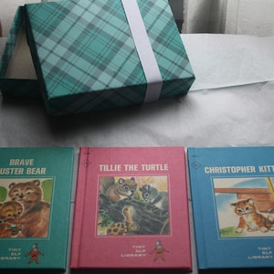 May include: Three hardcover children's books with colorful covers. The books are titled "Brave Buster Bear", "Tillie the Turtle", and "Christopher Kitten". Each book features a different animal on the cover and has the words "Tiny Elf Library" printed on the bottom.