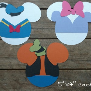 May include: Three paper cutouts of Disney characters: Donald Duck, Minnie Mouse, and Goofy. Each cutout is 5 inches by 4 inches. The cutouts are on a wooden surface.