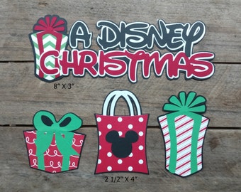 Puede incluir: Un conjunto de manualidades de papel con temática navideña de Disney con un esquema de colores rojo y verde. El conjunto incluye una pancarta que dice "A Disney Christmas", una bolsa de regalo con orejas de Mickey Mouse y dos cajas de regalo. La pancarta mide 8 pulgadas por 3 pulgadas, y la bolsa de regalo y las cajas miden 2 1/2 pulgadas por 4 pulgadas.