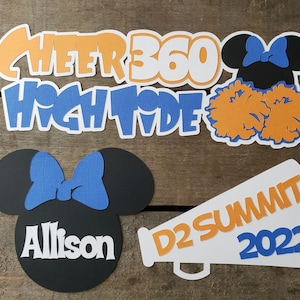 May include: Cheerleading themed paper cutouts with the text "Cheer 360 High Tide", "D2 Summit 2022", and "Allison". The cutouts feature a Mickey Mouse head with a blue bow, two orange pom-poms, and a megaphone.