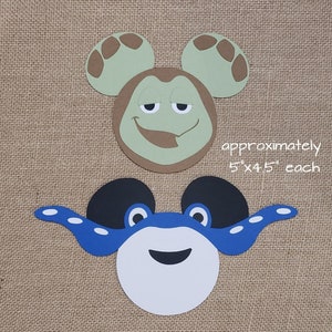May include: Two paper cutouts of cartoon characters with Mickey Mouse ears. The first cutout is green with brown accents and has a sleepy expression. The second cutout is blue with black accents and has a happy expression. The text "approximately 5" x 4.5" each" is written below the cutouts.