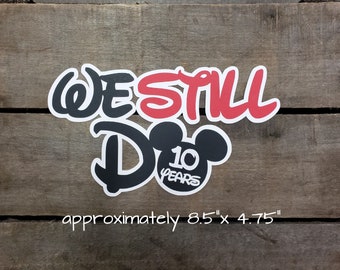 May include: Black and red cutout of the words "We Still Do" with a Mickey Mouse head and the number 10 inside the ear. The Mickey Mouse head has the words "10 Years" inside. The cutout is approximately 8.5 inches by 4.75 inches.