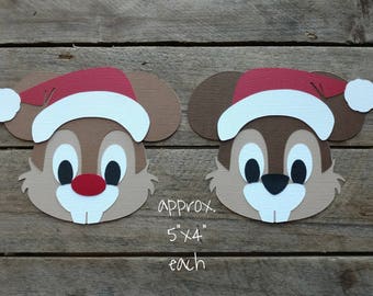 Puede incluir: Dos recortes de papel de un personaje de dibujos animados con un gorro de Papá Noel. El personaje tiene un pelaje marrón, ojos grandes y una nariz pequeña. Los recortes miden aproximadamente 5 pulgadas por 4 pulgadas.