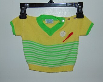 May include: Yellow short-sleeved knitted sweater with green and white stripes, a green v-neck, and a red and white baseball applique. The sweater has a label that reads "Kid Sport 100% Acrylic Fine Made in Japan."