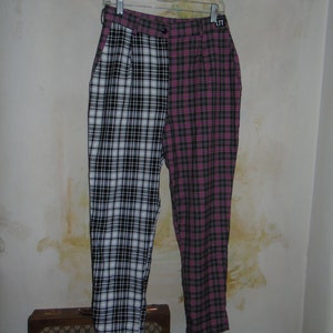 May include: Black and white plaid pants with a pink and black plaid panel on the right leg. The pants have a black belt and a small black tag with the word "LTT" on the back.