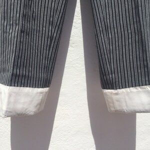 May include: A pair of black and white striped pants with white cuffs. The pants are made of a lightweight fabric and have a relaxed fit.