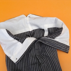 May include: Black and white striped pants with a white lining. The pants are turned inside out, showing the lining.
