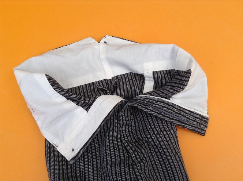 May include: Black and white striped pants with a white lining. The pants are turned inside out, showing the lining.