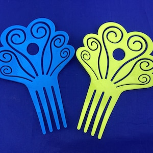 May include: Two plastic hair combs with a swirl design. One comb is blue and the other is yellow.