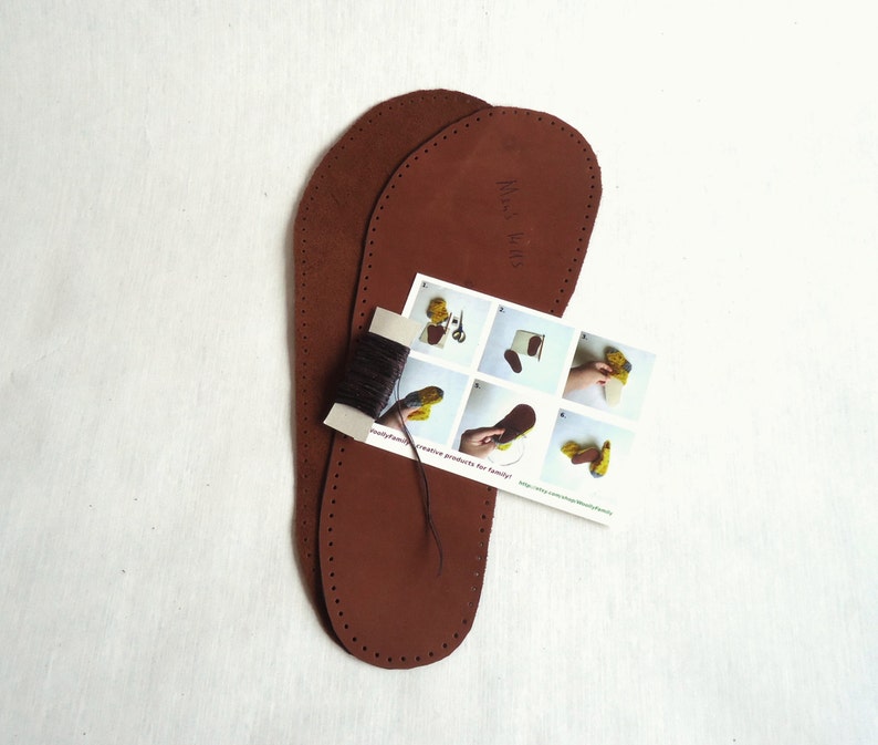 May include: Two brown leather soles for making moccasins. The soles are pre-punched with holes for stitching. A small instruction card with illustrations shows how to sew the moccasins. The card says "handmade creative products for family".