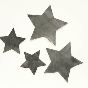 Puede incluir: Cuatro estrellas de papel grises de diferentes tamaños sobre un fondo blanco.