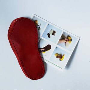 May include: Red leather sole with holes around the edge for sewing. The sole is on top of a sheet of paper with instructions for making a felt slipper.