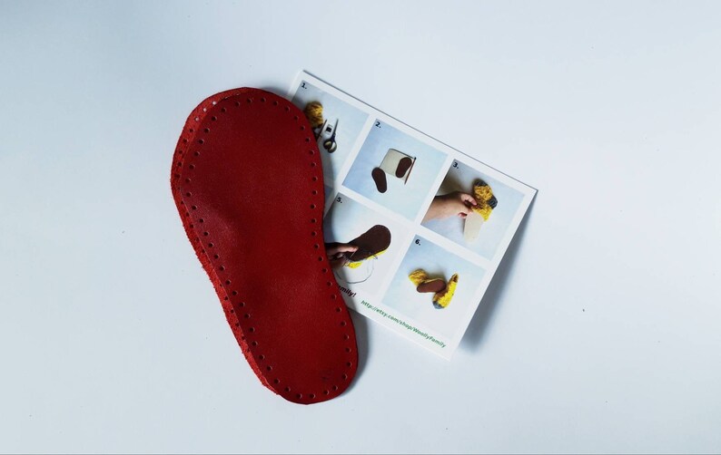 May include: Red leather sole with holes around the edge for sewing. The sole is on top of a sheet of paper with instructions for making a felt slipper.