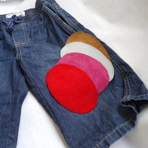 May include: A pair of blue denim shorts with five oval-shaped patches in various colours, including red, pink, white, and brown.