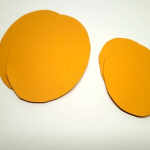 May include: Two yellow felt circles, one larger than the other. The larger circle is made of two layers of felt.