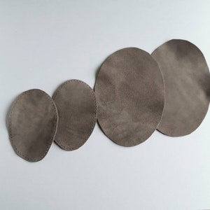 May include: Four brown suede circles of different sizes, stitched around the edges.
