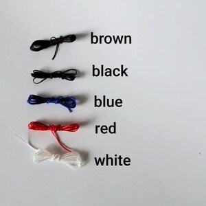 May include: Five spools of thread in different colors: brown, black, blue, red, and white.