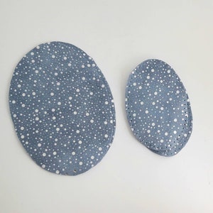 Könnte beinhalten: Zwei blaue, ovale Stoffstücke mit einem weißen Tupfenmuster. Das größere Stück ist etwa 15 cm lang und das kleinere etwa 7,5 cm lang.