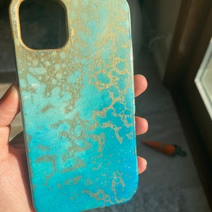 May include: A blue and gold phone case with a marbled design. The case has a raised edge around the camera lens.